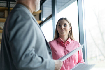 Obraz premium Mature businessman and young business woman professional corporate executive leaders discussing strategy documents