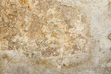 Close-up of a heavily textured and crumbling old plaster or concrete wall surface. The rough, damaged facade shows signs of decay and age, ideal for a grunge background or industrial design element. © Aliaksei