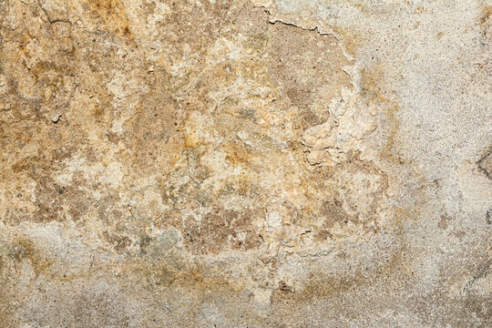 Close-up of a heavily textured and crumbling old plaster or concrete wall surface. The rough, damaged facade shows signs of decay and age, ideal for a grunge background or industrial design element.