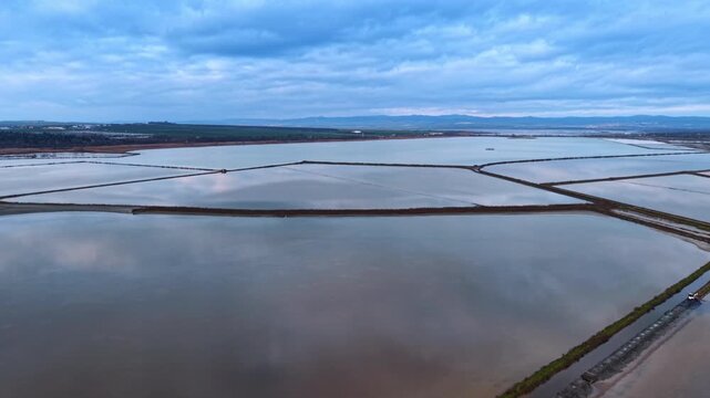 Geometric patterns of coastal salt evaporation ponds. Aerial view of water pans with dikes and dambs near the sea coast.