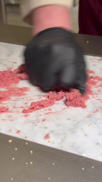 Hand-kneading traditional Lebanese Kibbeh Nayyeh, chef preparing fresh raw meat dish in restaurant kitchen.