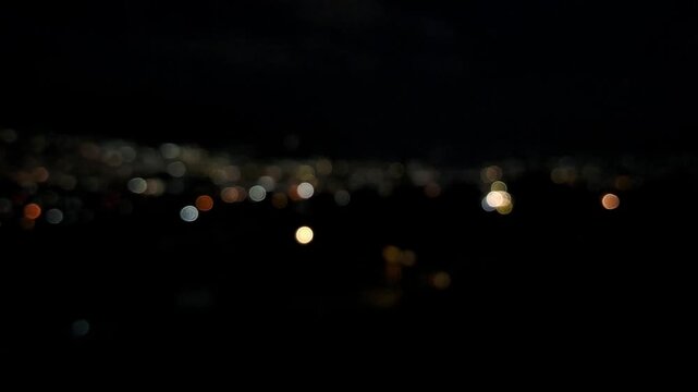Handheld night view of Batu city&rsquo;s sparkling lights seen from a villa hillside, creating a dreamy bokeh effect that resembles glowing stars scattered across the landscape.
