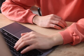 Obraz premium Man working on laptop at wooden desk, closeup