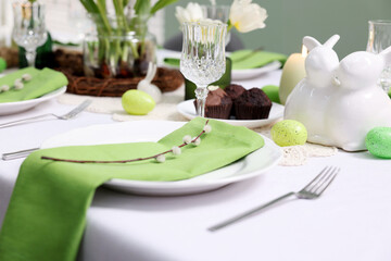 Fototapeta premium Easter celebration. Festive table setting with elegant dishware and willow branches, closeup