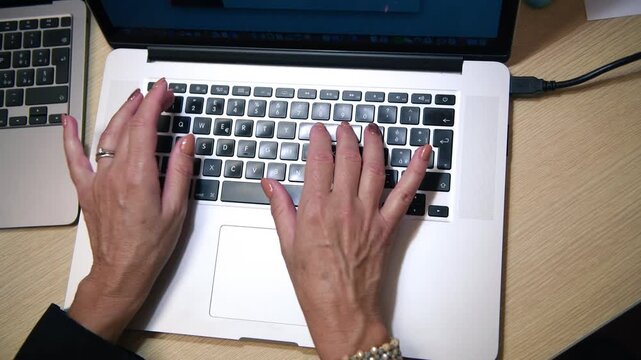 Woman working with his laptop in the office, downward view, detail on the keyboard