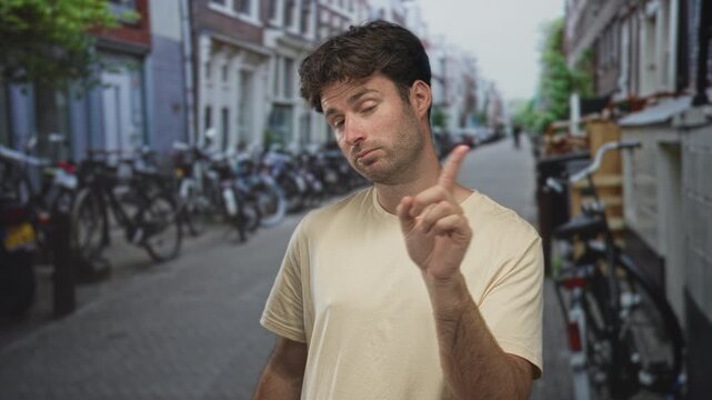 Man with finger to lips for silence on a city street framed by rows of parked bicycles and narrow buildings; hush.