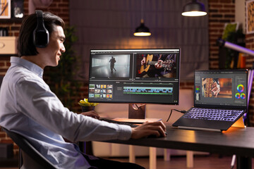 Cheerful freelancer editing film soundtrack at home and comparing videos on multiple devices on...