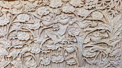 Obraz premium Detailed Indonesian limestone carving of a lotus pond with a stork and flowers. Background texture.