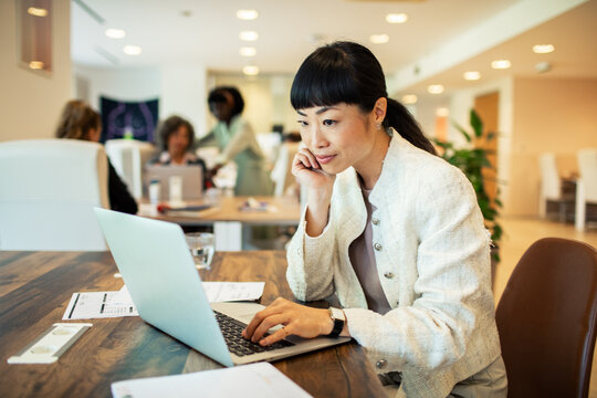 Focused businesswoman using laptop in modern coworking office
