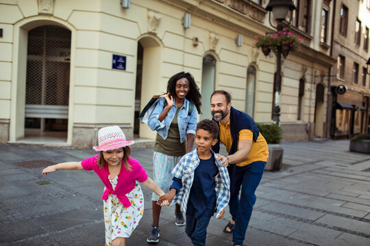 Parents and two kids running on city street