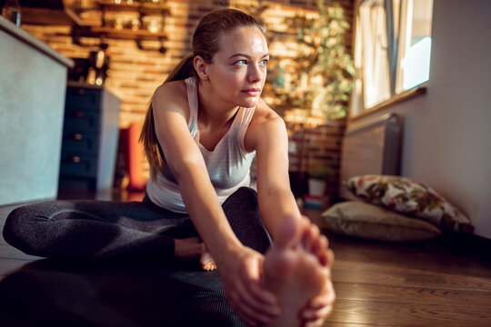 Young woman stretching on yoga mat at home