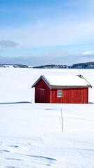 A vibrant red, snow-covered shack stands on a vast, frozen expanse under a bright blue sky, mirroring the serene winter landscape