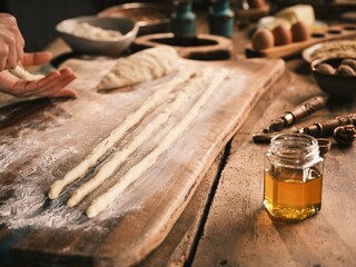 Hands skillfully shape sweet dough into long strands while preparing mucenici, a traditional Moldovan dessert celebrating the 40 martyrs