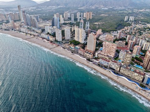 seaside neighborhood with sandy shoreline, aerial perspective showcasing tranquil coast and urban backdrop