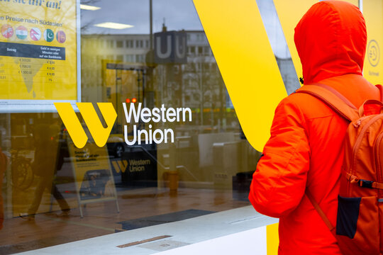 Western Union Company yellow logo, Global money transfer modern branding, cross-border connectivity, urban street scene with pedestrians and buildings, financial services branch in Hannover, Germany