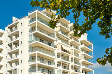 Contemporary Modern residential buildings facade with balconies under clear blue sky, community with lush greenery, modern architecture_ well-maintained landscape, apartment buildings city lifestyle © kittyfly