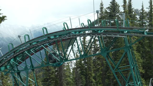 Slow motion footage of gondolas moving near cable support structure at the mountain summit station.