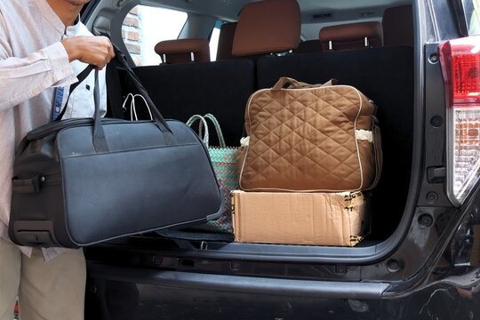 An Asian Muslim man puts his bag in the trunk of his car. Preparations for the Eid homecoming.