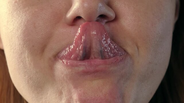 Close up video of a woman sticking out her tongue and successfully touching the tip of her nose with it.
