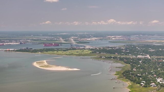 Panoramic aerial view of Arthur Ravenel Jr. Bridge and container ship in Charleston, South Carolina lowcountry landscape showing cityscape, waterway, and homes from Sullivan's Island - 4K Drone