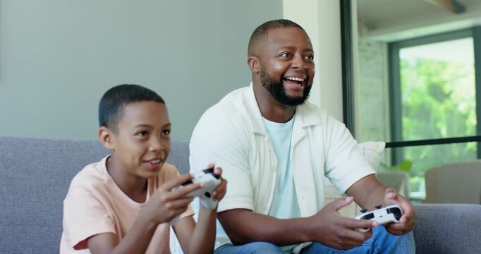 African American father and teen son with controllers, bonding while playing game at home, laughing