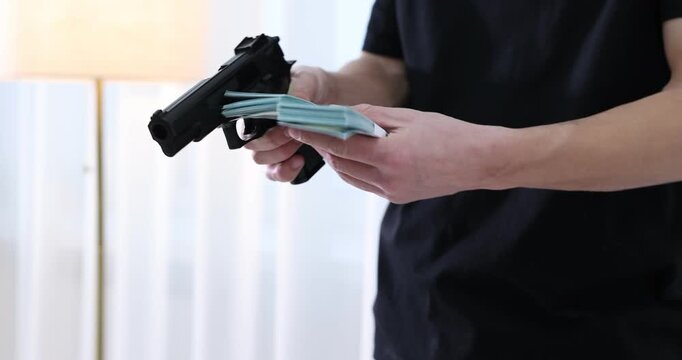 Woman giving money to dangerous criminal with gun indoors, closeup. Armed robbery