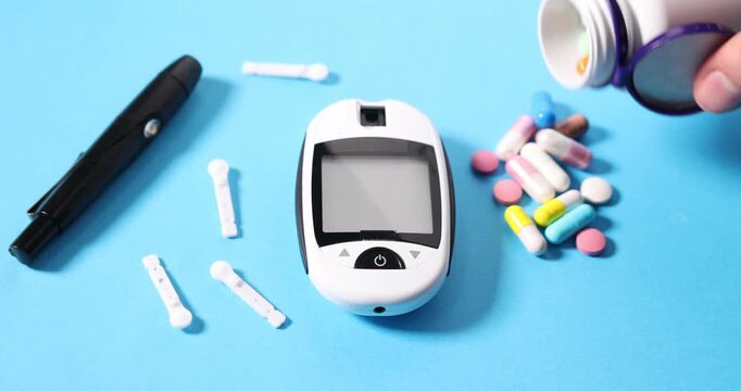 Diabetes. Woman pouring pills from bottle near digital glucometer, pen and lancets on light blue table, closeup