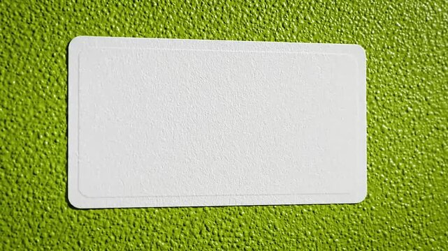 White rectangular sticker peeling off a vibrant green textured surface.