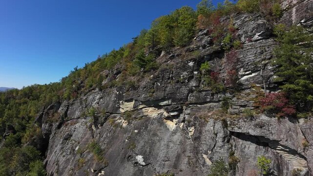 Majestic Cliff With Pine Pockets. Imposing Vertical Face With Steep Drop Into Wooded Valley. Dramatic Natural Formation Showcasing Layered Rocks And Dense Forested Surroundings