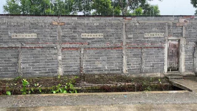 Concrete brick wall exterior of rural building under daylight with simple architectural structure. Modest construction scene creating neutral, practical, and functional atmosphere suitable for urban d