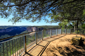 View of Grose Valley from Evans Lookout in the Blue Mountains highlighting rugged and weathered sandstone cliffs above dense forest wilderness.