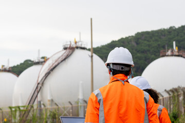 Back view of Professional technical team at a fuel and energy plant, Industrial engineers using a laptop for technical data analysis at a gas storage facility