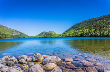 A beautiful lake with a rocky shoreline and mountains in the background