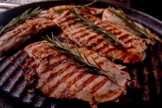 bifes de pollo con rama de romero en plancha de hierro.