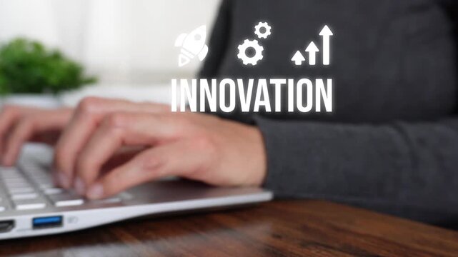 Close-up of a woman's hand working on a computer pointing to an animation of the word "Innovation" with rocket, gear, and arrow icons.