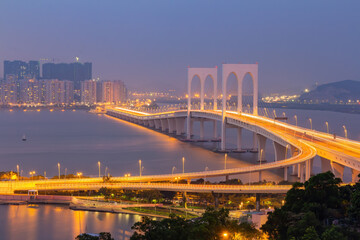 Obraz premium Modern cable stayed bridge glows at twilight over harbor waters.