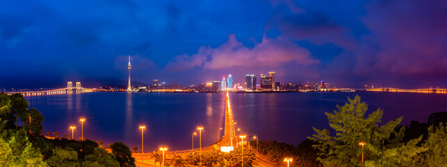 Luminous city skyline at twilight over water.