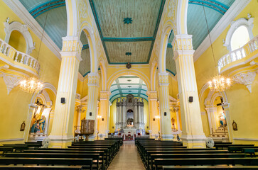Yellow and teal church interior with arched columns and chandeliers. © Kit Leong