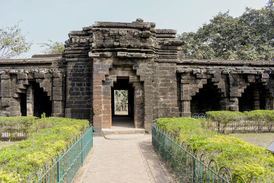 ​a centered view of a stone entrance gate from inside the kurumbera fort, showing the rugged laterite masonry, tiered architectural details, and a pathway leading through the historical courtyard gard