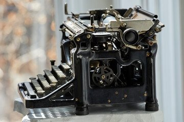 An old manual typewriter with black cast-iron body and round keys is a classic piece of vintage office equipment