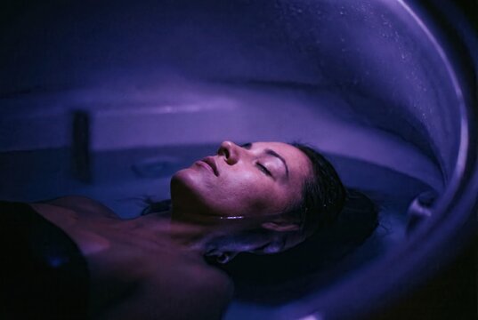 Serene woman meditating in sensory deprivation float pod