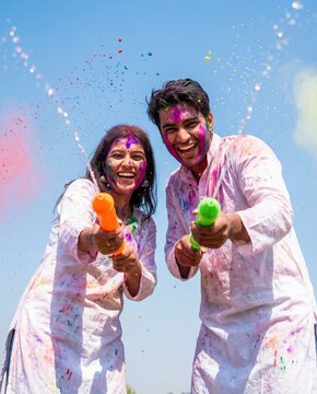Couple celebrating Holi with colors and pichkaris