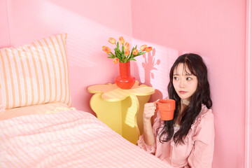 ピンク背景の部屋でリラックスするアジアの若い女性のポートレート