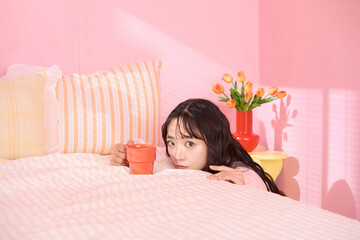 ピンク背景の部屋でリラックスするアジアの若い女性のポートレート