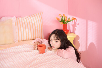 ピンク背景の部屋でリラックスするアジアの若い女性のポートレート