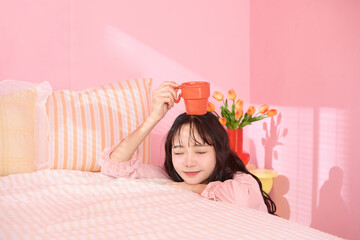 ピンク背景の部屋でリラックスするアジアの若い女性のポートレート