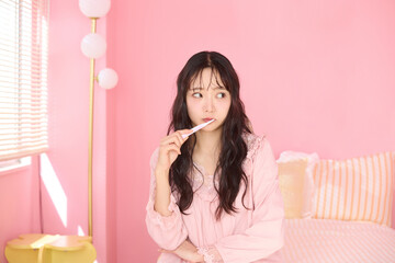 ピンク背景の部屋でリラックスするアジアの若い女性のポートレート