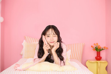 ピンク背景の部屋でリラックスするアジアの若い女性のポートレート