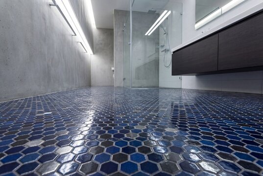 Blue hexagonal mosaic tile floor in modern concrete bathroom