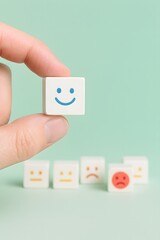 Obraz premium Hand holding a smiling face emoticon cube with other emoticons